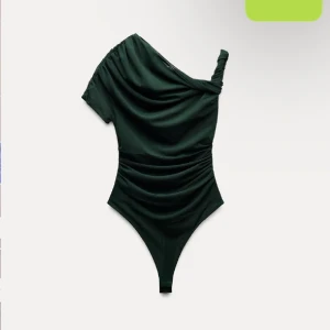 Svart oneshoulder bodysuit - Snygg svart oneshoulder bodysuit med draperad design. Perfekt för en stilren och modern look. Passar bra till både jeans och kjol. Helt ny med prislappen kvar