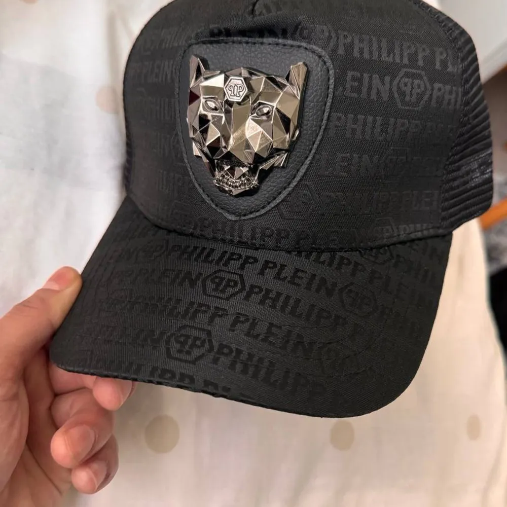 Snygg svart keps från Philipp Plein med ett coolt mönster och en iögonfallande metallisk djurdetalj framtill. Perfekt för att ge din outfit en edgy touch.. Asusteet.