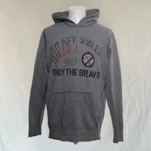 Grå hoodie från Diesel - Snygg grå hoodie från Diesel med texten 'Only the Brave' och 'Kraft Werk' i olika färger på framsidan. Tröjan har en klassisk känguruficka och en bekväm huva. Perfekt för en avslappnad stil.