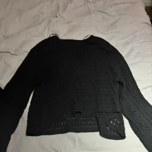 Svart stickad tröja - Säljer en svart stickad tröja med långärmad design. Tröjan har ett luftigt stickmönster och en avslappnad passform. Perfekt för kyligare dagar och att matcha med olika outfits.