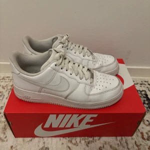 Vita Nike Air Force 1 '07 - Säljer ett par klassiska vita Nike Air Force 1 '07 sneakers. Skorna har en stilren design med snörning. Skorna kan enkelt rengöra för att se näst intill nya.
