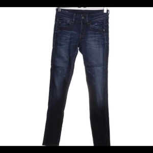 Mörkblå jeans från G-Star RAW - Snygga mörkblå jeans från G-Star RAW i modellen Slander Denim. De har en tight passform och är tillverkade i ett stretchigt material för extra komfort. Perfekta för en stilren look.