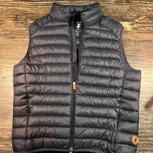 Save The Duck väst - En svart snygg väst från Save The Duck. Säljer på grund av att storleken är för liten.                               Står XL men passar L mycket bättre. Alltså liten i storleken. Använd ett fåtal gångar och har inga defekter!                                                                              Nypris: 1400kr