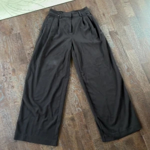 Svarta kostymbyxor från Kappahl - Snygga svarta kostymbyxor från Kappahl i storlek 34. Byxorna har en hög midja och vida ben. Perfekta för fest eller finare tillfällen. Hör gärna av er vid frågor och funderingar🫶🫶