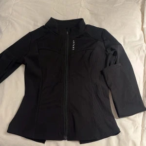 Svart träningsjacka från Astani - Snygg svart åtsittande träningsjacka från Astani. Fint skick! Använd endast ett par gånger.