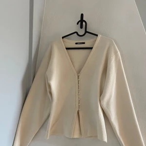Beige kofta från Gina Tricot - Säljer en stilren beige kofta från Gina Tricot i storlek XS. Koftan har en v-ringad design med knappar framtill och långa ärmar. Perfekt för en elegant och avslappnad look. Helt som ny!!!❤️❤️
