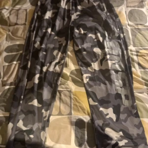 Camouflage GASP gymbyxor  - Säljer ett par helt nya oanvända träningsbyxor från GASP med klassiskt grått och svart camouflagemönster. Byxorna har flera praktiska fickor och en loose passform, perfekt för en avslappnad stil.