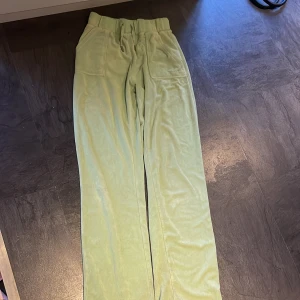 Gröna frottébyxor med fickor - Snygga gröna byxor i frotté med hög midja och avslappnad passform. Byxorna har praktiska fickor både fram och bak, med knappar på bakfickorna för extra stil. Perfekta för en bekväm och trendig look.