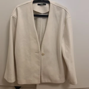 SUPERFIN VÅRJACKA🤍🤍 - Elegant vit jacka från bikbok med en enkel knapp framtill. Den har en stilren design med långa ärmar och en klassisk passform. Perfekt för en stilren look.