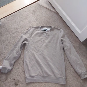 Beige sweatshirt från Sustainable Clothing Essentials - Stilren beige sweatshirt från Sustainable Clothing Essentials. Tröjan har en klassisk rund hals och långa ärmar. Tillverkad med hållbara material för en miljövänlig garderob. 🌿 Beige/grå ish, sitter som M/L på mig som är 172cm lång