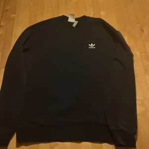 Mörkblå sweatshirt från Adidas - Säljer denna mörkblå sweatshirt från Adidas, då jag har tröttnat på den. Har används måttligt, men fortfarande i riktigt bra skick!