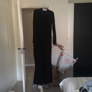 Svart jumpsuit med krage - Elegant svart jumpsuit med krage och långa ärmar. Perfekt för en stilren look.