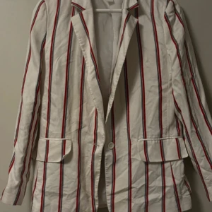 Vit/röd randig kavaj från H&M - Snygg vit/röd kavaj från H&M i storlek 38. Kavajen har klassisk design med knappar framtill och fickor på sidorna. Bild på kan lösas❤️