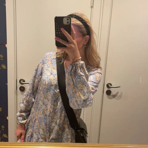 Blommig klänning från Soyaconcept - Säljer en söt blommig klänning från Soyaconcept i ljusblått och beige. Klänningen har långa ärmar och ett avslappnat snitt som ger en bekväm passform. Perfekt för en somrig look!