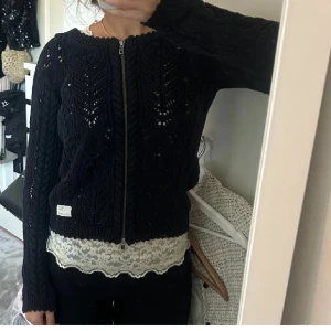 Svart stickad kofta från Odd Molly - Säljer en snygg svart stickad kofta från Odd Molly med dragkedja framtill. Koftan har ett vackert stickat mönster och långa ärmar. Perfekt för att hålla sig varm nu men också till sommaren! 