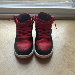 Nike Air Jordans i svart och rött - Snygga Nike Air Jordans i svart och rött med klassisk design. Skorna har snörning och en vit sula som kontrasterar snyggt mot det svarta och röda lädret. Perfekta för dig som vill ha en stilren och sportig look.
