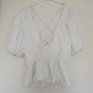 Topp - Vit topp/blus med volang och puffärmar. Med knyte i ryggen. Kom gärna med prisförslag går med på det mesta. 