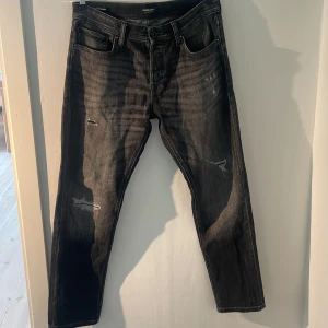 Svarta jeans från Jack & Jones - Säljer ett par snygga svarta jeans från Jack & Jones. De har en tapered passform och är i modellen 'Mike'. Jeansen är varsamt använda och är i ett skick 9/10. Är i storlek 32 vilket passar dig som är 175-185 cm. Hör gärna av er vid frågor eller funderingar!