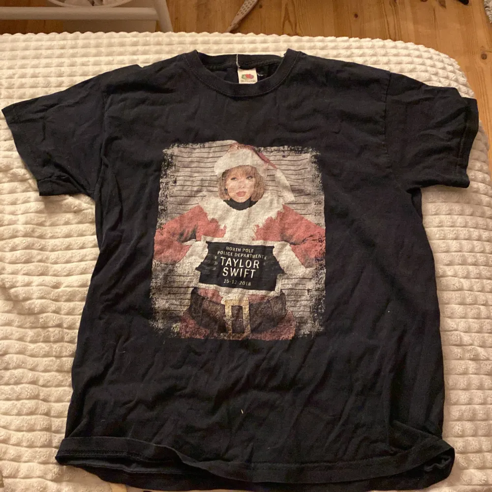 Säljer en svart T-shirt med ett coolt julmotiv på framsidan. Trycket föreställer en person i tomtedräkt med texten 'North Pole Police Department' och datumet 25-12-2018. Perfekt för julfesten eller som en rolig present! T-shirten är i bomull och har korta ärmar.. T-shirts.