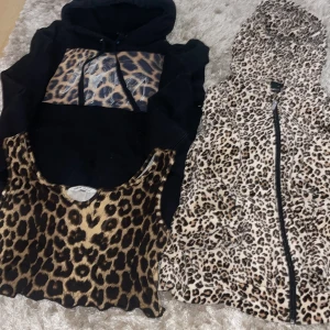 Leopardmönstrad hoodie och väst från Shein - Säljer en cool svart hoodie med leopardmönstrad elefanttryck på bröstet för 50kr och en matchande leopardmönstrad tröja med dragkedja 60kr även ett linne med leopard mönster för 15kr. Perfekt för en djärv och trendig look! Båda plaggen är i bra skick och redo för nya äventyr. 🐆paketpris fixas