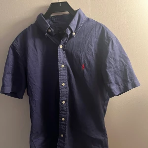 Ralph lauren skjorta  - En kortärmad Ralph lauren skjorta.Det är inget fel på skjortan och den har mycket kvar att ge. (Kan även bytas!)