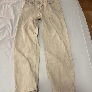 Beige jeans från Bershka - Säljer ett par beige jeans från Bershka i storlek EUR 34. De är i modellen '90s WIDE' och har en avslappnad passform. Byxorna har en dragkedja och knapp framtill samt två bakfickor. Perfekta för en casual look!