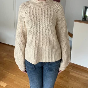 Vit stickad tröja från Soyaconcept - Säljer en superfin vit stickad tröja från Soyaconcept. Den är perfekt för höst och vinter med sin mysiga och varma känsla. Tröjan har en hög krage och långa ärmar med ribbade muddar. Den är i nyskick och passar perfekt till både jeans och kjol. Perfekt för att hålla sig varm och snygg under de kallare månaderna! ❄️