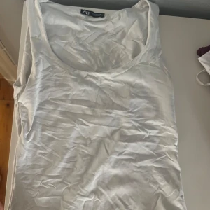 Vit linnetopp från ZARA - Säljer en enkel och stilren vit linnetopp från ZARA. Perfekt för sommardagar eller som ett basplagg i garderoben. Toppen är ärmlös och har en rund halsringning.