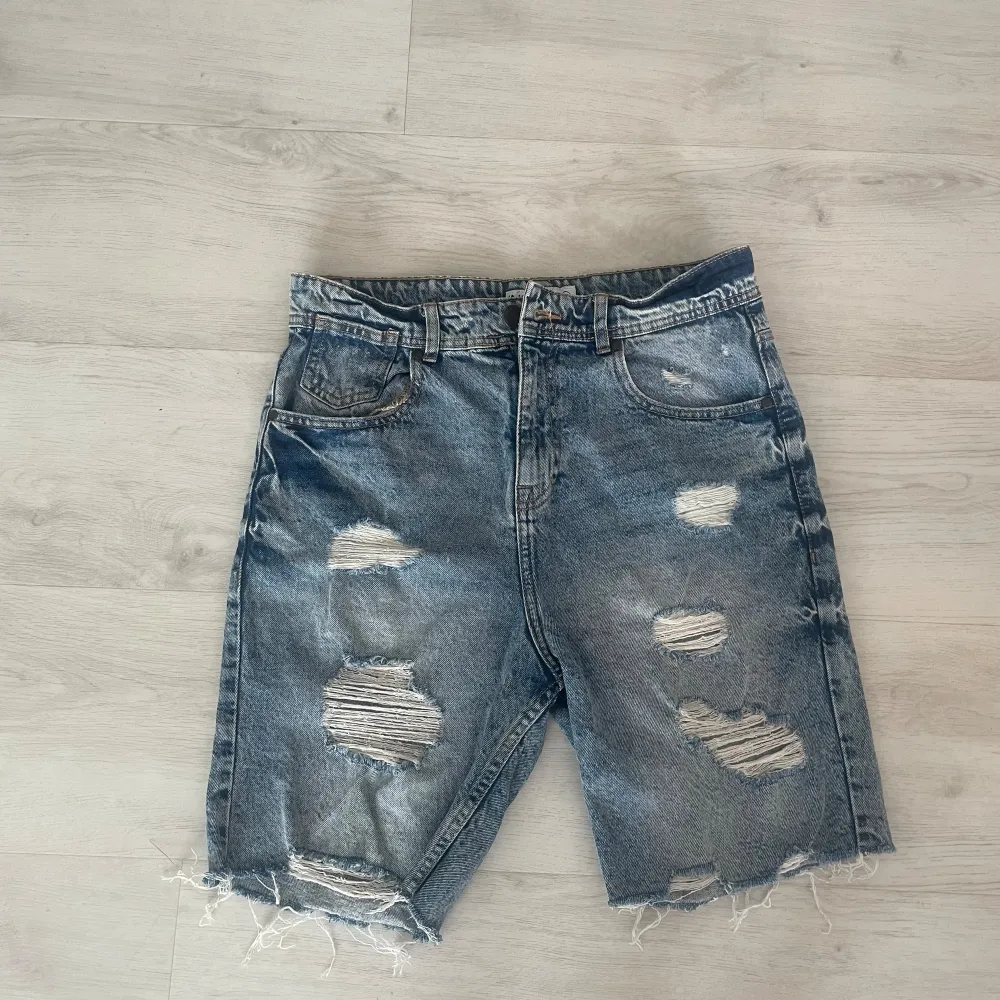 Ett par vanliga jeansshorts i gråblå färg med slitningar. Så gott som oanvända. Köpta i Spanien så storleken som står motsvarar ungefär M. . Shorts.