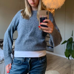 Grå stickad tröja - Säljer en mysig grå stickad tröja med lång ärm. Perfekt för kyliga dagar och passar bra till jeans eller kjol. Tröjan har en normal passform och är superbekväm att ha på sig. Perfekt för höst och vinter!