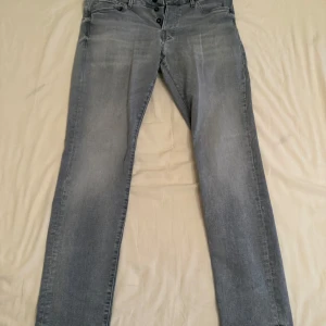 Jack & Jones slim fit jeans grå - Snygga grå slim fit jeans från Jack & Jones med en klassisk straight passform. De har en knappgylf och är tillverkade i ett slitstarkt denimtyg. W34 L32