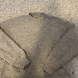 Grå stickad tröja från Shein - Säljer en mysig grå stickad tröja från Shein. Tröjan har en klassisk design med långa ärmar och ribbade muddar vid ärmslut och nederkant. Perfekt för kyligare dagar.