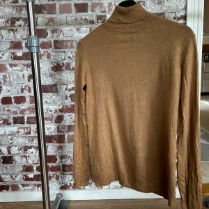 Brun polotröja från Vila - Säljer en stilren brun polotröja från Vila. Tröjan har långa ärmar och en klassisk polokrage, perfekt för kyligare dagar. Den är tillverkad i ett mjukt material som ger en bekväm passform.