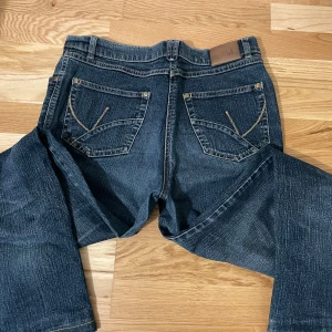 Mörkblå jeans från Kello - Snygga mörkblå jeans från Kello med klassisk femficksdesign och kontrastsömmar. Perfekta för en avslappnad stil. Märkeslogga på baksidan av midjan.
