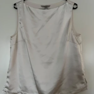 Sidentopp, H&M, M, beige - Beige sidentopp från H&M i storlek M, i nyskick. Tjockare material, dvs ej genomskinlig. 100% polyester.   Mått:  Längd ca 60 cm Byst ca 45 cm