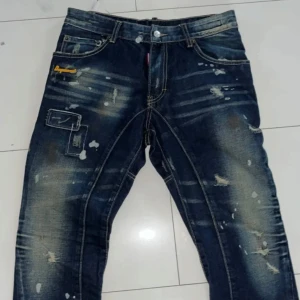 Blå jeans från Dsquared2 - Snygga blå jeans från Dsquared2 med slitna detaljer och jeansen är extremt unika och snygga. Jeansen har en klassisk femficksdesign och dragkedja vid bensluten. Tillverkade i 100% bomull för en bekväm passform. De har inga skador pch 9/10 kvalité. Va inte rädd att ställa frågor