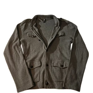 Grå Cardigan - Säljer en stilren grå bomulls cardigan i storlek 175 (M) från H&M