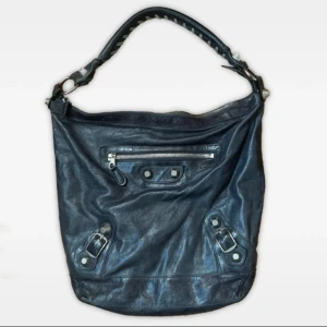 vintage 00s svart balenciaga day bag/hobo bag väska distressed leather äkta skinnväska - Säljer en fett snygg trendig svart axelväska från Balenciaga i äkta skinn. flätad axelrem med coola silver hardware detaljer. köpt från vintage-hemsidan “labelsmostwanted” som garanterat autencitet. bild på det engriverade serienumret visar också att det är en äkta balenciagaväska. kommer med en spegel och en dustbag. minimala repor på en av silverlänkarna vid axelbandet (se sista bilden) men dessa kan snurras så det inte syns alls. bra vintage skick! 