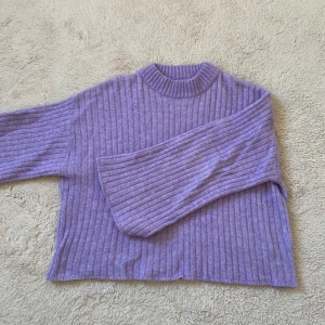 Lila ribbad tröja från Stockh LM Studio - Säljer en snygg lila ribbad tröja från Stockh LM Studio. Tröjan har en hög krage och långa och utsvängda ärmar, perfekt för kyligare dagar. Säljer då den inte längre används 💜💘