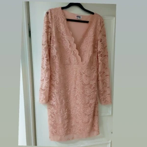 Rosa spetsklänning från Make Way  - Elegant rosa klänning i spets från Make Way med v-ringad design. Klänningen har långa ärmar och ett vackert blommönster som ger en romantisk känsla. Perfekt för speciella tillfällen.Liten i storlek,  mera som L I storlek. 