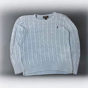 Ljusblå kabelstickad tröja från Ralph Lauren - Säljer en stilren ljusblå stickad tröja från Ralph Lauren med klassiskt kabelstickat mönster. Tröjan har långa ärmar och en broderad logotyp på bröstet.  Storlek: 10-12 vilket motsvarar ungefär XS. Perfekt för kyligare dagar. Mycket bra skick. Hör av er vid frågor!😊