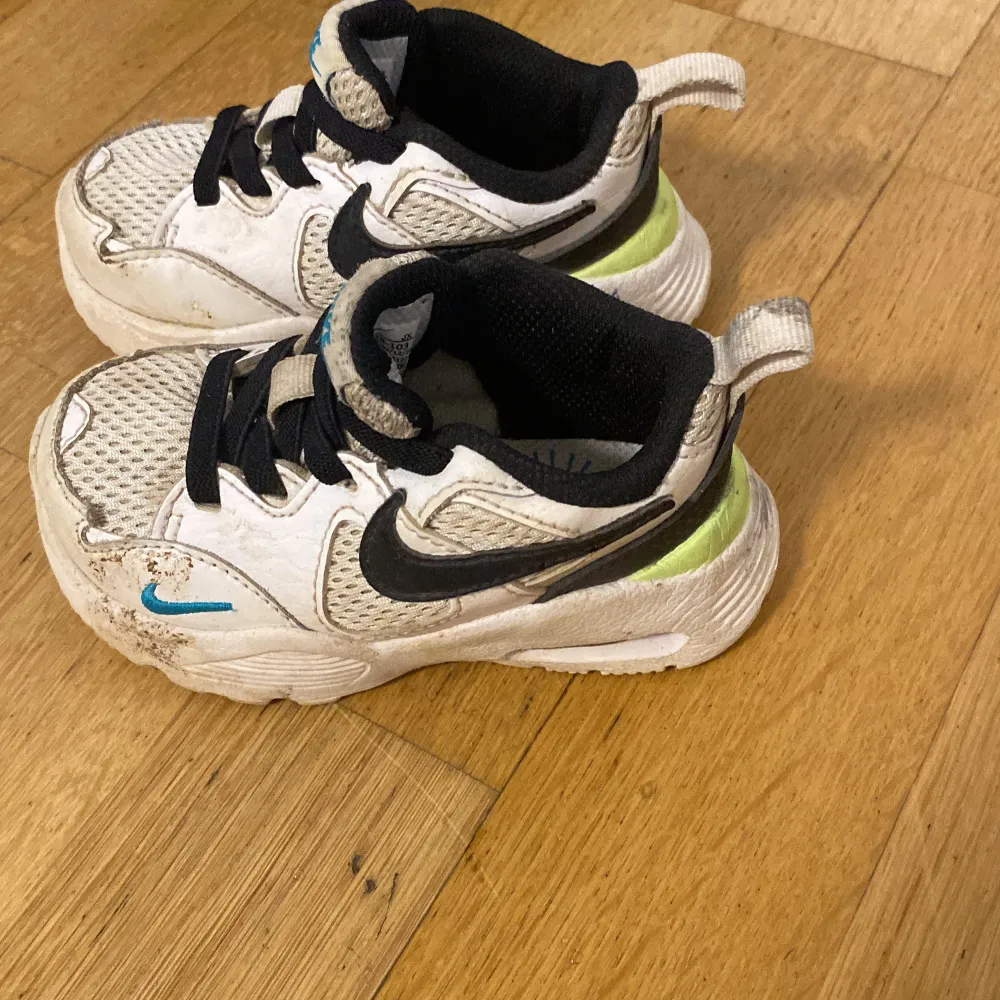 Säljer ett par vita och svarta Nike sneakers med blå detaljer. Skorna har snörning och en bekväm passform, perfekt för vardagsbruk. De har en sportig design med märkets logga på sidan och tungan. Vid snabb affär sänks priset. Kengät.
