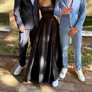 Svart balklänning från JJ's House - Svart balklänning med smala axelband och en slits framtill. Klänningen har en öppen rygg med korsade band och knytning. En sömmerska har sytt upp klänningen inte i längden utan sytt upp släpet, släppet på klänningen finns kvar så man har möjlighet att sy ner det igen. Det följer med en garmet bag som man kan förvara klänningen i utan att den blir skrynklig. Jag är 169 och den passar perfekt för mig i längden, använd 1 gång. St 34/xs-s, pris 1300kr köpt för 1700kr