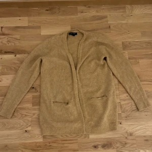 Beige stickad kofta  - Säljer en mysig beige stickad kofta. Koftan har långa ärmar och två fickor framtill. Perfekt för kyliga dagar och enkel att matcha med olika outfits.