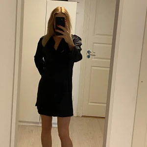 Figursydd skjortklänning i blank satin från H&M - Figursydd skjortklänning i satin från H&M Syns ej på bild, men otroligt glansigt och skönt material. Långa ärmar, lite styvare tyg vid handlederna med slits. Populär modell som sålde slut snabbt. Stlk 40. Säljer även  en likadan vit i stlk 38.