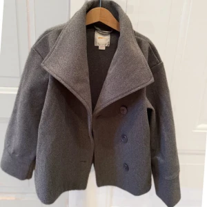 Grå kappa från Gina - Säljer en grå kort kappa från gina young i storlek 158/164. Har använts varsamt så knappt tecken på användning. 