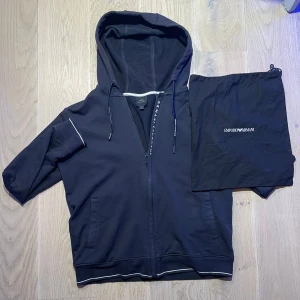 Svart huvtröja från Armani Exchange - Säljer en stilren svart huvtröja från Armani Exchange med dragkedja och vita detaljer.  Dustbag medföljer .