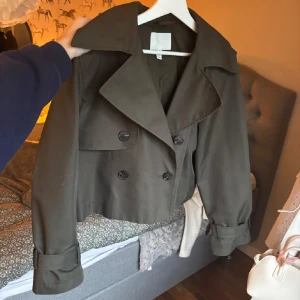 Kort kappa  - !Lånade bilder! Säljer denna sjukt snygga korta trenchcoat från H&M! Slutsåld och nypris är 550kr. Nytt skick och så fin färg! Sitter bra på mig som vanligtvis har S