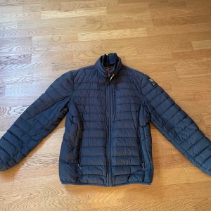 Svart dunjacka från Parajumpers - Säljer en svart superlätt dunjacka från Parajumpers. Jackan har en dragkedja framtill och är quiltad för extra värme. Perfekt för kyliga dagar med sin stilrena design och bekväma passform. Passar storlek M.