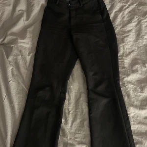 Svarta kostym byxor från BikBok - Snygga kostymbyxor från BikBok, Perfekta för en stilren look. Byxorna har en klassisk design med knappar och dragkedja framtill.